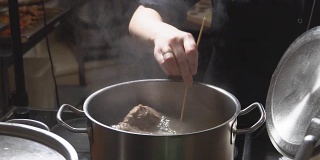 餐馆厨房里，金属锅里沸腾的肉汤。高清