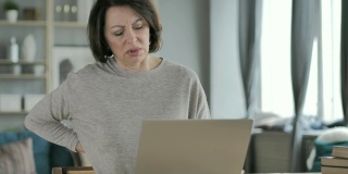 背疼的老女人用笔记本电脑工作