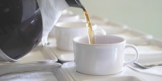 用茶壶将热茶倒入会议用的茶杯中