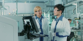 亚洲工程师与女主管谈话，用电脑编程印刷线路板表面贴装装配线的取放电子机械。使用SMT设备生产PCB。