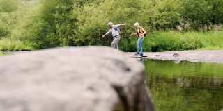 在英国湖区徒步旅行时用垫脚石过河的老年夫妇的慢动作镜头