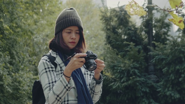 年轻的亚洲女子在中央公园用单反相机拍照。纽约