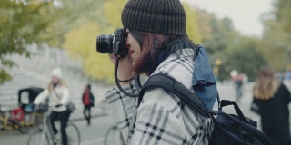 年轻的亚洲女子在中央公园用单反相机拍照。纽约
