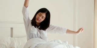 女人早上从床上醒来，感觉很放松。人以放松，生活方式，醒观念。