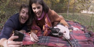 一名男子用手机自拍，他的妻子和他的狗
