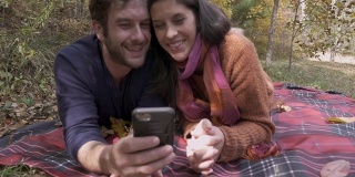 波士顿梗躺在一对夫妇旁边用他们的智能手机自拍