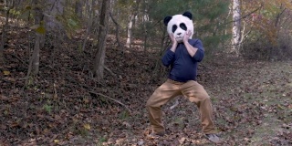 一名戴着熊猫头面具的男子在公园外面跳舞庆祝