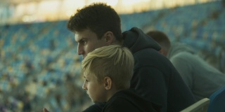 两兄弟在体育场看足球，一起度过时光，友谊