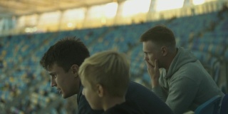 兄弟俩在体育场看少年足球比赛，讨论输掉的比赛
