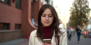 年轻女子拿着智能手机在城市里行走，用稳定器拍摄