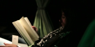 一个女人在一晚上旅行的公交车上看书
