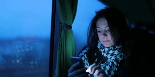 一名女子在晚上乘公交车时使用手机。女孩晚上上网查邮件