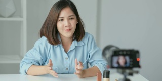 年轻的亚洲女性美容博主展示化妆品，同时记录如何用相机制作视频教程，视频博客的概念，美丽和时尚人士和技术交流