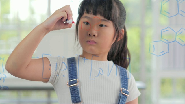 小女孩在学校上课用马尾辫写字，用笔在透明的板子上学习科学，智慧，年轻的学生动机和成功的教育理念。教育的主题