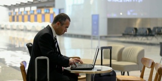 在机场用笔记本电脑工作的商人
