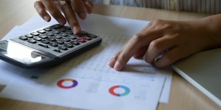 近距离观察商业女性会计用计算器计算财务数据表，商业和财务概念