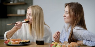 两个漂亮的女孩在家吃日本菜。卷在盘子里是不一样的，很好吃