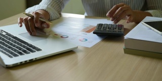 近距离观察商业女性会计用计算器计算财务数据表，商业和财务概念