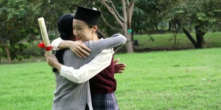 年轻的亚洲女毕业生在毕业典礼上拥抱她的朋友。国际多元化背景