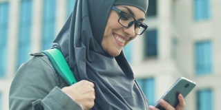 快乐的阿拉伯女孩用智能手机，在大学课后与朋友聊天