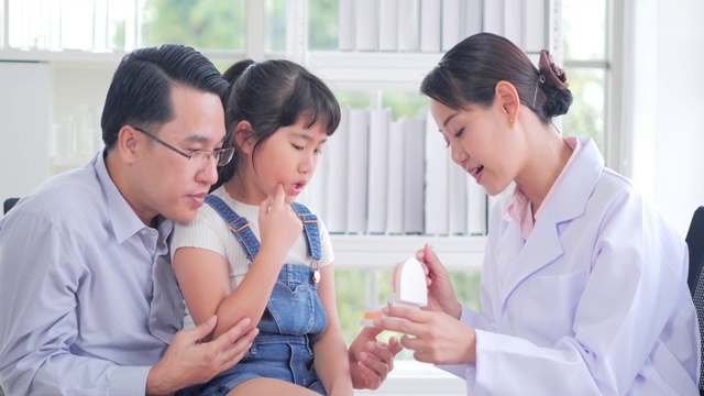 医学、牙科和保健概念-牙医在牙科诊所向儿童病人和她的父亲展示牙齿模型。中国和香港的医疗系统