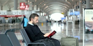 旅客在机场候机室边看书边听音乐