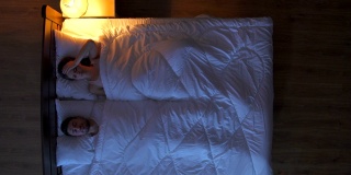 患头痛的妇女躺在床上。晚上的时间。从上面的观点