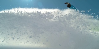慢镜头特写:欢快的滑雪者雕刻和喷雪到摄像机