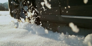 慢镜头:在阳光明媚的日子里，一辆汽车驶离公路，吐出了几块湿雪。