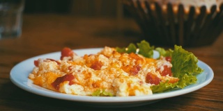 餐厅木桌上的一盘格鲁吉亚煎蛋卷，配上番茄、奶酪和香草。