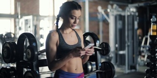 健康的年轻女子在健身房使用手机