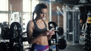 健康的年轻女子在健身房使用手机视频素材模板下载
