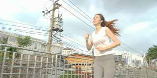 年轻迷人的女人在城市里跑步锻炼。健身跑步运动的人与健康的生活理念。