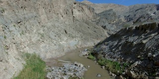 无人机在巨大的岩石峡谷中从一条孤独的河流中拉回