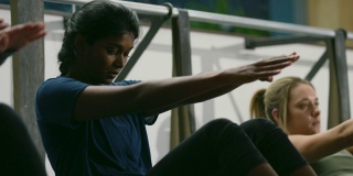 一位二十多岁的亚洲印度妇女与一组妇女在巴利健身工作室交替进行腹部锻炼