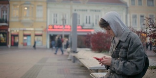 青少年男孩在城市环境中听音乐和使用电话