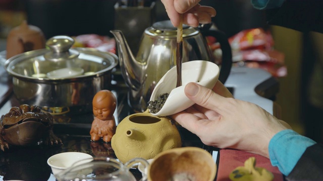 茶道。师傅用木勺把绿茶舀进茶壶里