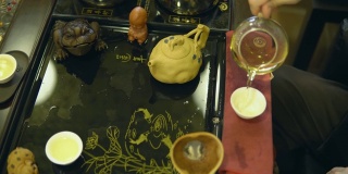 茶道。师傅将绿茶从玻璃茶壶中倒入白色杯子中