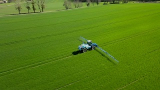 鸟瞰图农用肥料在农田上工作，农业机械在耕地上工作，喷洒农药视频素材模板下载