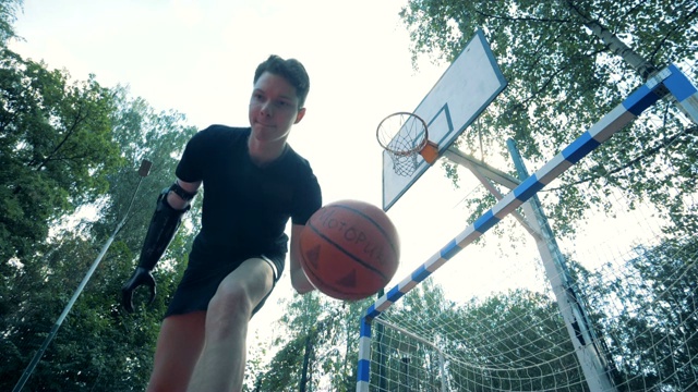 一个年轻人用一个未来派的义肢表演一个篮球的慢动作杂耍