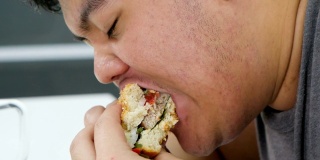 近距离照片的人吃汉堡和饥饿的人吃。真实的身体