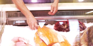食品销售，小型企业和海鲜概念-男性卖家把鲑鱼或鳟鱼排放入冰箱在鱼店