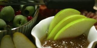 室内庆祝/派对上，用平底锅近距离平底锅拍摄的绿橄榄和石榴(种子)在一个装饰碗里，旁边是一碗蜜饯和苹果片，餐刀放在开胃盘的顶部