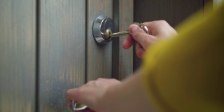 女人用钥匙打开大门。使用钥匙和锁门的人员。房地产安全概念