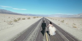 美国死亡谷，新郎和新娘在空旷的沙漠路上奔跑