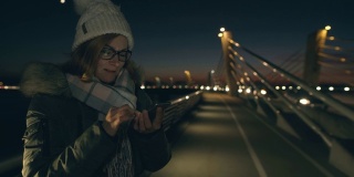 晚上在桥上用智能手机发短信的女士