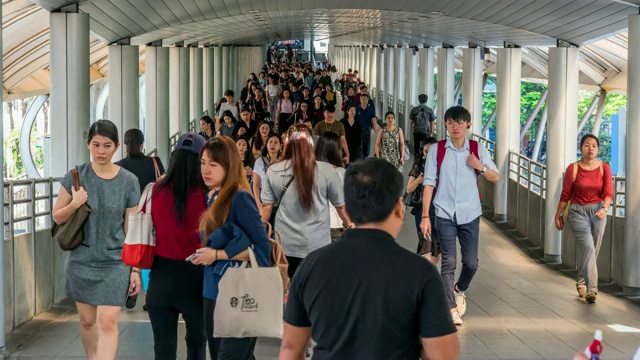 在曼谷BTS Chong Nonsi的高峰时刻，拥挤的人在高架地铁系统站的天桥上行走，交通和乘客旅行的概念