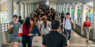 在曼谷BTS Chong Nonsi的高峰时刻，拥挤的人在高架地铁系统站的天桥上行走，交通和乘客旅行的概念