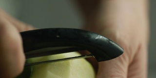 一个女人的手剥一个绿色苹果与蔬菜削皮器的极端特写镜头