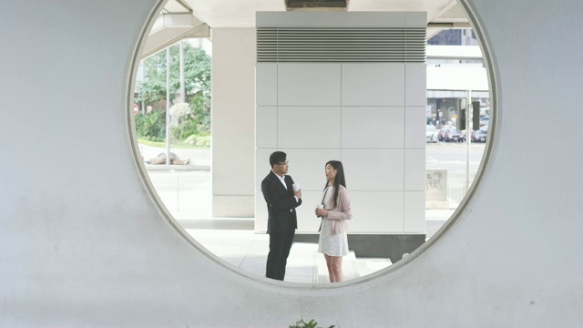 两个中国商人在室外的圆形建筑后面交谈